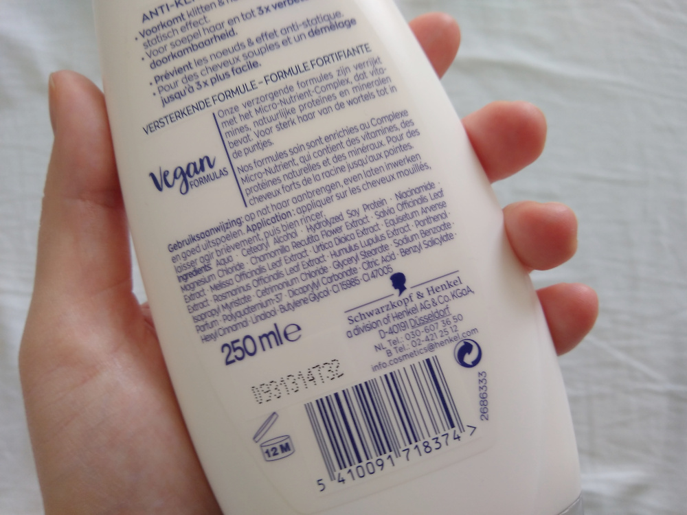 A hand holding a bottle of conditioner with the ingredient list up. One of the first ingredients is a protein, hydrolyzed soy protein.