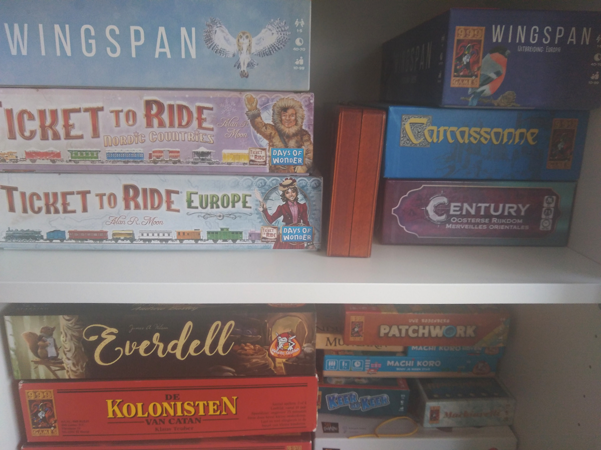 Several board games and other table top games on shelves, including Wingspan, Ticket to Ride, Carcassonne, Century, Everdell, Catan, Patchwork and Machi Koro.